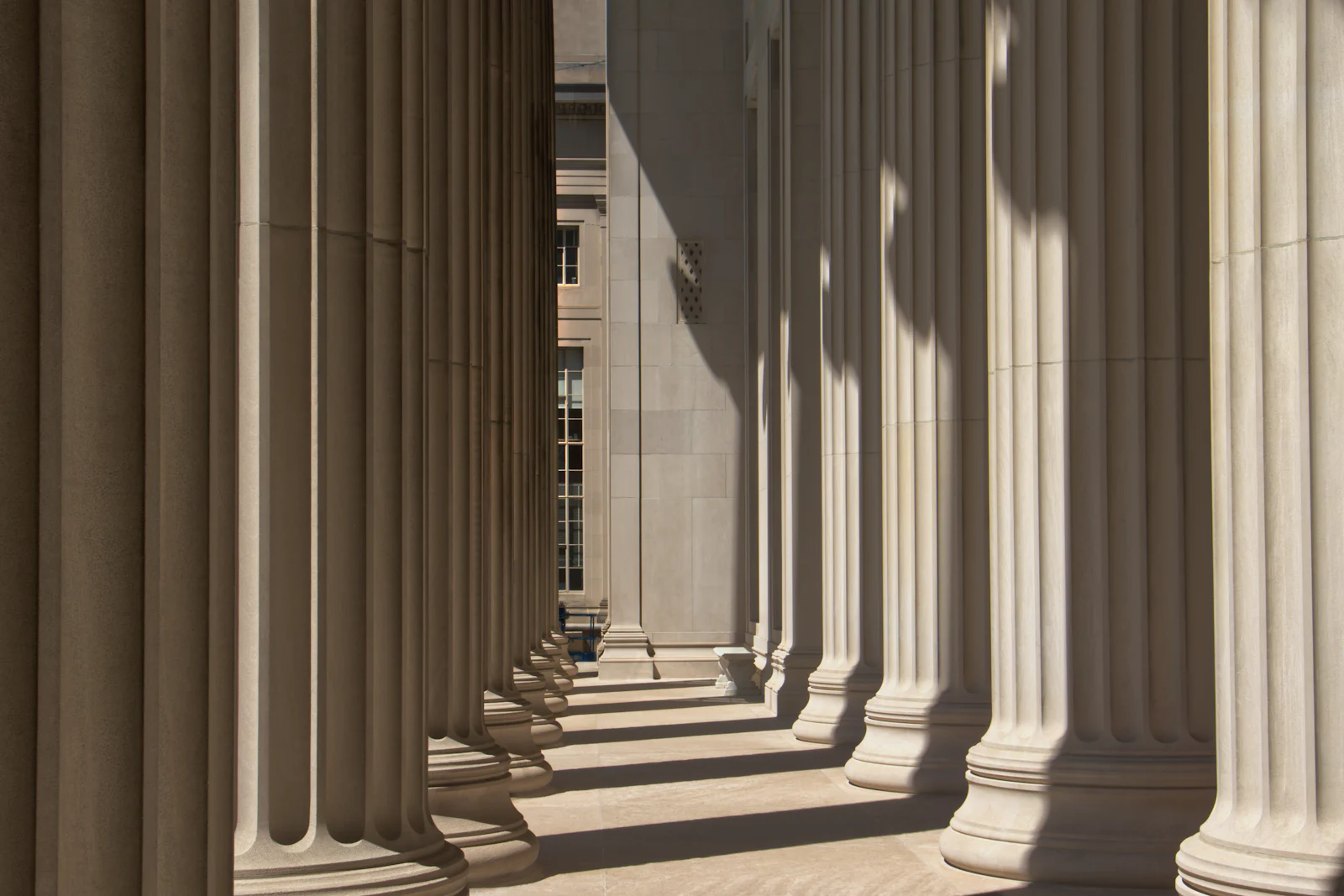 A row of stone columns casting long shadows in the sun